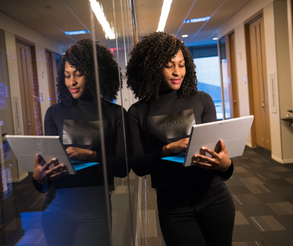 woman leaning on glass holding laptop