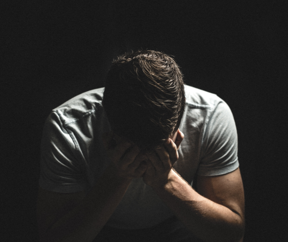 man bent over with head placed down in hands