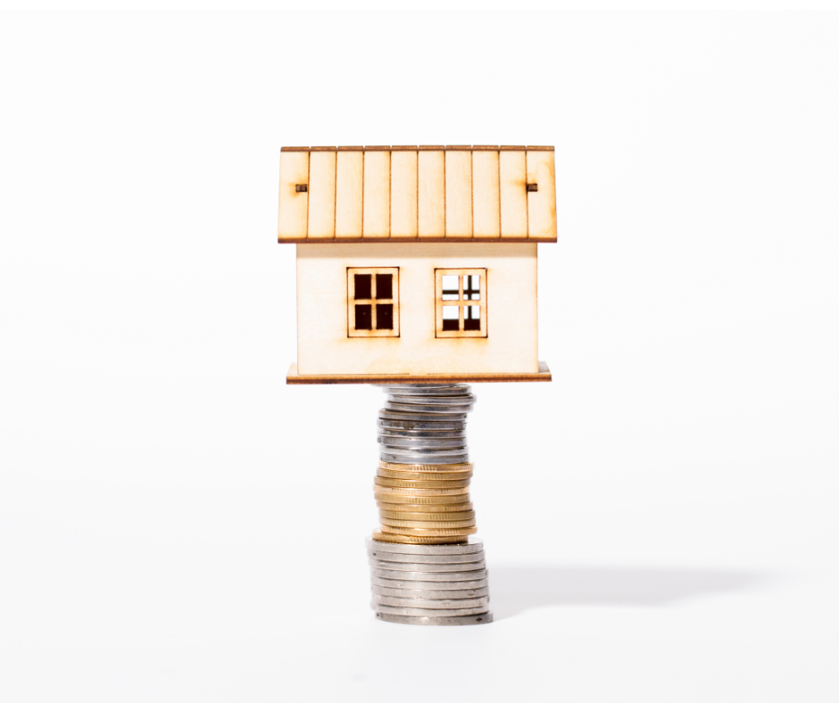 small wooden house on stack of coins