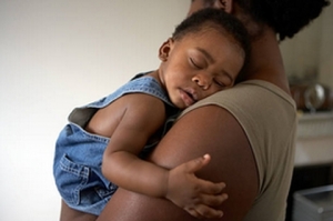 a woman holding a sleeping child