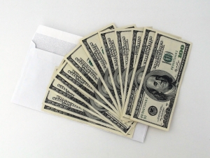 a stack of $100 bills spread like a hand of cards on top of a white envelope