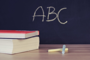 chalkboard reads "ABC" with books in foreground