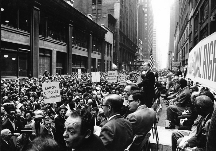 black and white image of a group of people holding signs that read "labor opposed discrimination"