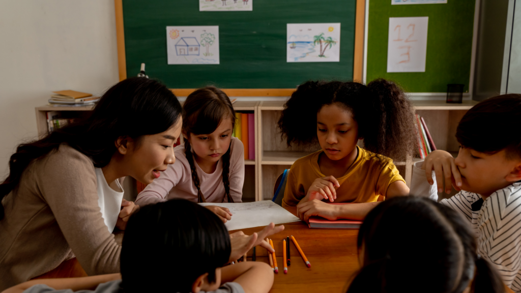 group of children sitting at a table in a circle with teacher